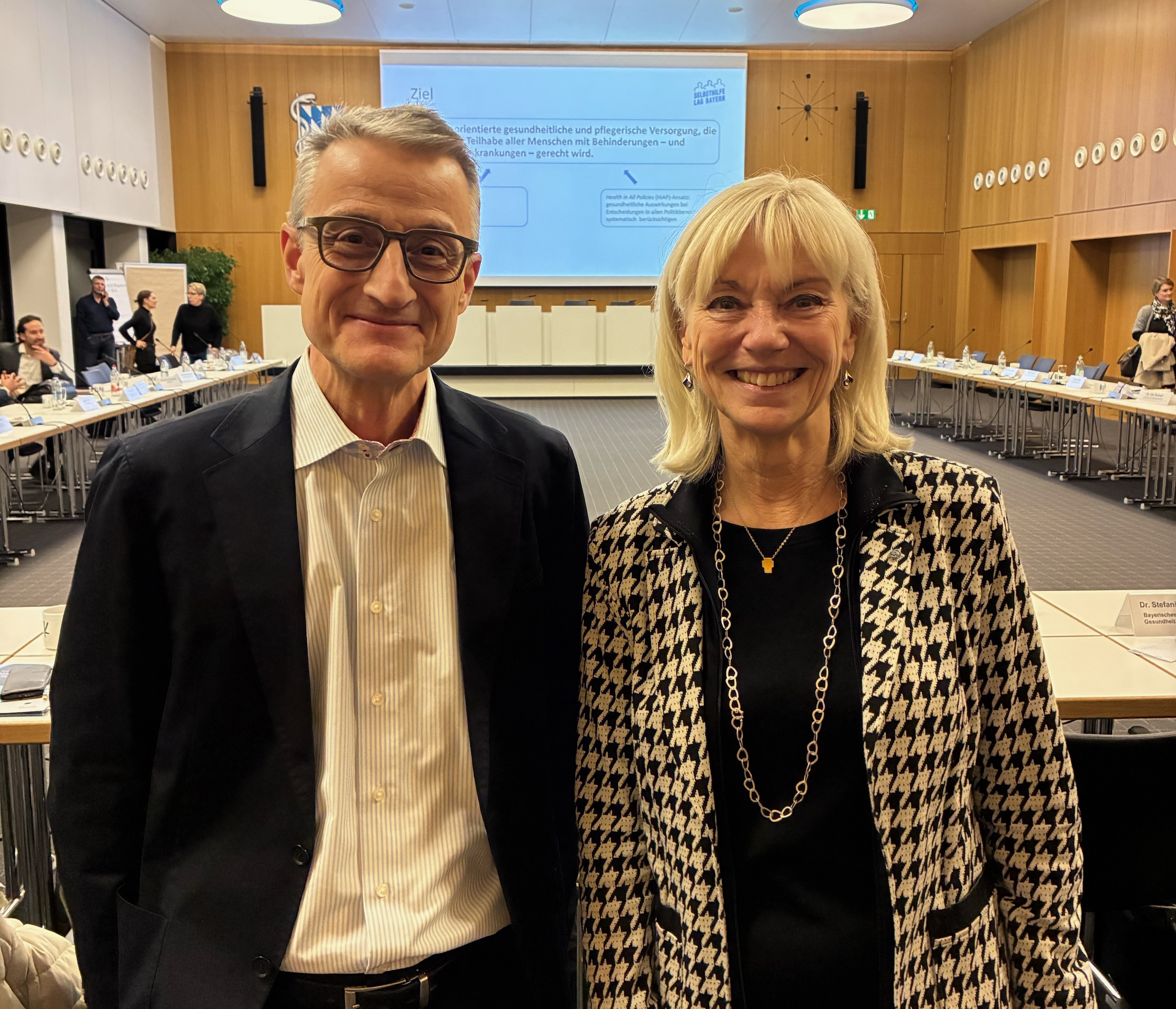 Ein Mann und eine Frau stehen in einem Sitzungssaal.